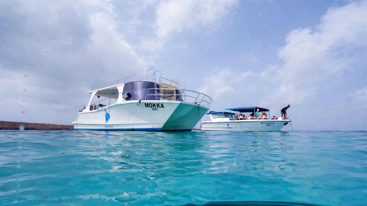 Catamaran with a sundeck anchored in calm water at the Daymaniyat Islands on a snorkeling and BBQ tour from Muscat, Oman